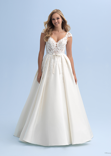 A bride wearing a wedding dress with cap sleeves and a belted waist with a semi full skirt
