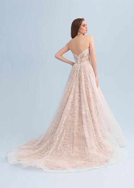 A woman looking over her shoulder wearing a lacy wedding dress with a long train