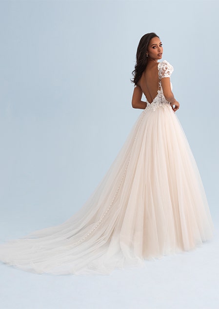 A woman looking over her shoulder wearing a wedding dress with a tulle skirt and train