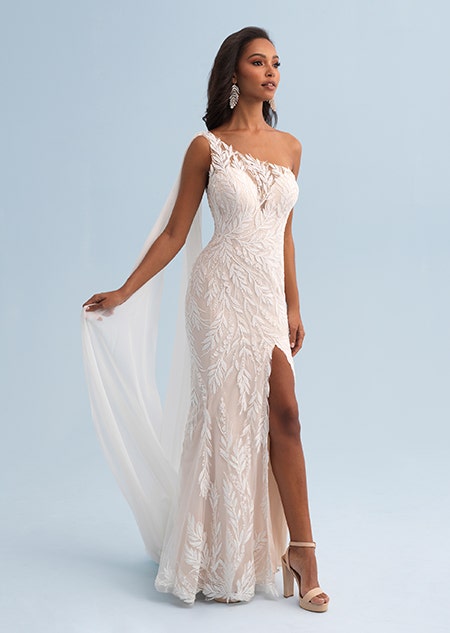 A woman wearing a form fitting wedding dress with a lace leaf pattern and asymmetrical sleeves