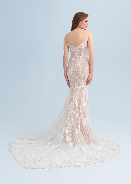 A woman looking over her shoulder wearing a form fitting and strapless wedding gown with lace