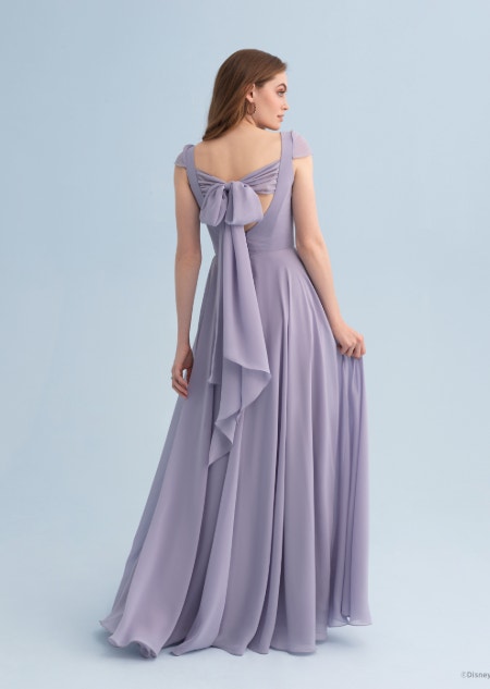 A woman wearing a Rapunzel themed bridesmaid dress with a bow across the back