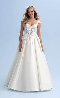A bride wearing a wedding dress with cap sleeves and a belted waist with a semi full skirt