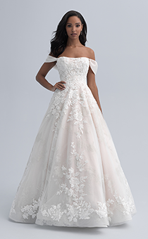 A bride in an off the shoulder dress with straps hanging above her elbows and a full skirt adorned with large flowers