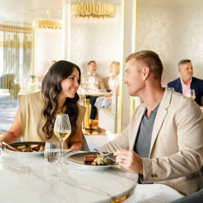 A man and a woman smiling at each other while sitting at a table in Enchante