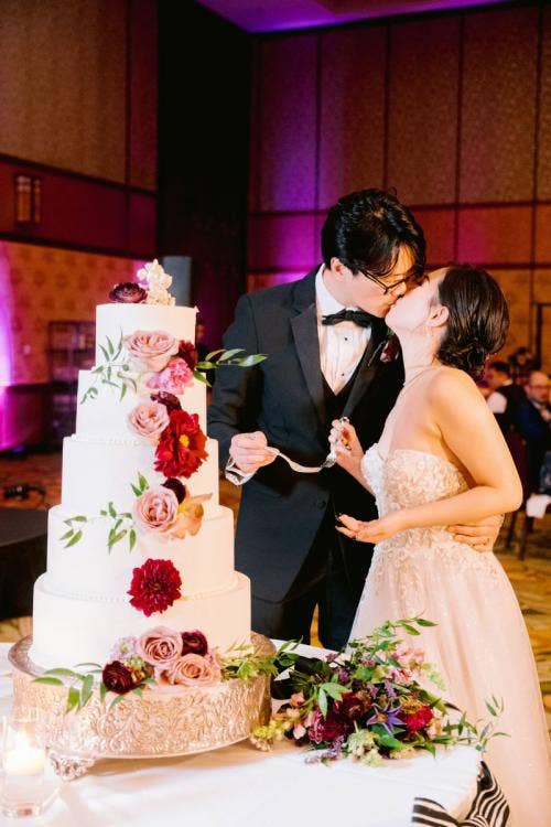 bride and groom, couple, cutting cake, wedding cake, cake, moody aesthetic, moody floral, halloween theme, 5 tier cake, grand californian, grand californian ballroom