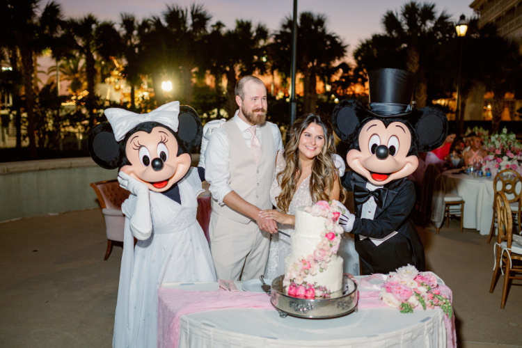 bride and groom, couple, cutting cake, wedding cake, cake, mickey and minnie, characters, entertainment, wedding reception, reception, summerhouse patio, grand floridian