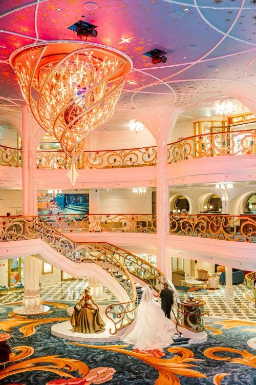 bride and groom, couple, portrait, disney wish, disney cruise line, cruise line, disney cruise, cruise, grand hall, disney wish grand hall, chandelier, grand staircase, kiss goodnight, disney wish kiss goodnight