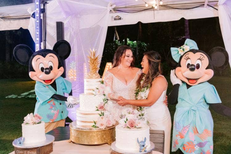 LGBTQ, couple, bride bride, cutting cake, 3 tier cake, wedding cake, characters, entertainment, Mickey Mouse, Minnie Mouse, mickey and Minnie, wedding reception, reception, Aulani, lanikuhonua, lanikuhonua reception