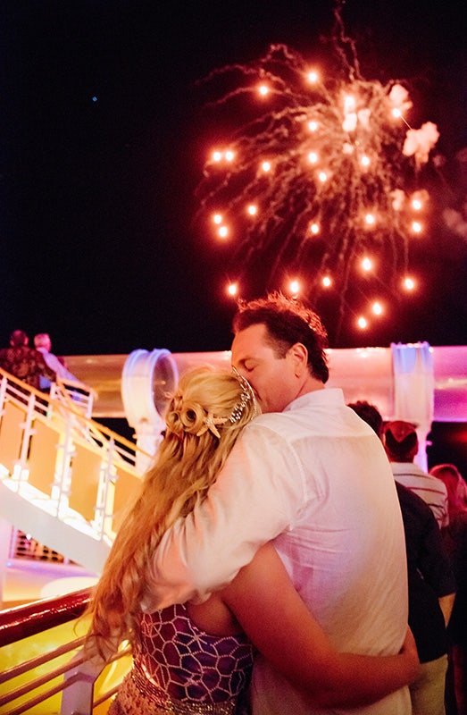A groom kissing his bride as she watches the fireworks