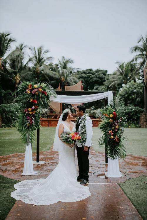 bride and groom, couple, portrait, couple portrait, wedding ceremony, ceremony, altar area, altar decor, altar floral, tropical floral, tropical, white drape, palm fronds, colorful floral, altar arch, flower crown, lei, halawai lawn, aulani