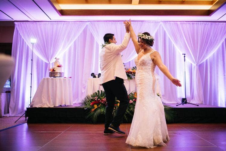 bride and groom, couple, first dance, wedding reception, reception, custom up lighting, white drape, drapery wall, tropical floral, sweetheart table, floral, flower crown, lei, palm fronds, colorful floral, aulani, ka'ala ballroom, ka'ala