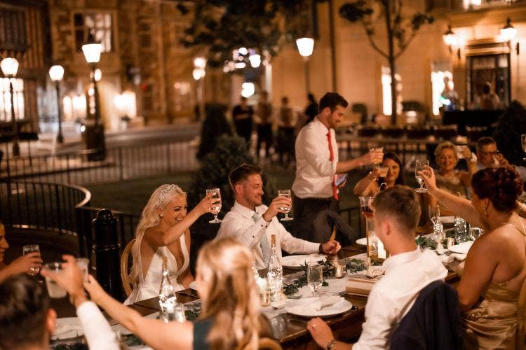 wedding reception, reception, decorated reception, long table, custom chairs, table runner, custom centerpieces, reception decor, lanterns, table decor, Epcot, Epcot reception, uk, uk pavilion, uk courtyard, cheers, toast, champagne toast