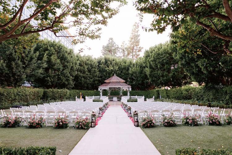 venue shot, decorated venue, wedding ceremony, ceremony, disneyland, disneyland hotel, disneyland resort, rose court, rose court garden, aisle floral, aisle decor, aisle lanterns, black lanterns, halloween, halloween theme, moody aesthetic, moody floral