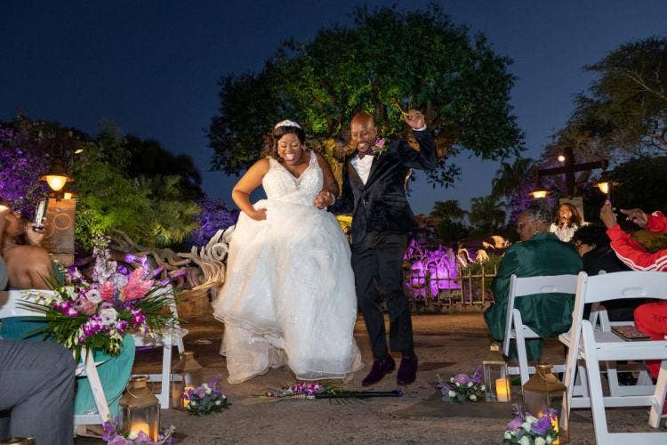 bride and groom, couple, candid, wedding ceremony, ceremony, animal kingdom, disney's animal kingdom, tree of life, custom up lighting, up lighting, broom, hopping over broom