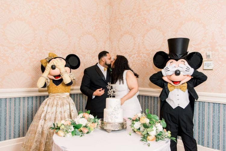 bride and groom, couple, candid, kiss, couple kiss, wedding reception, reception, cutting cake, cake, wedding cake, entertainment, mickey and minnie, mickey mouse, minnie mouse, characters, grand floridian, grand floridian ballrooms