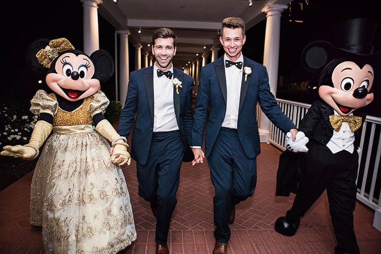 Grooms walking with Mickey and Minnie Mouse
