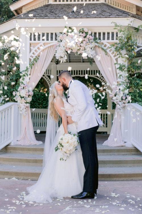 bride and groom, couple, portrait, wedding ceremony, ceremony, boho, boho floral, petal toss, kiss, Disneyland, Disneyland Hotel, rose court, rose court garden