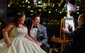 Couple with caricaturist at an outdoor wedding reception