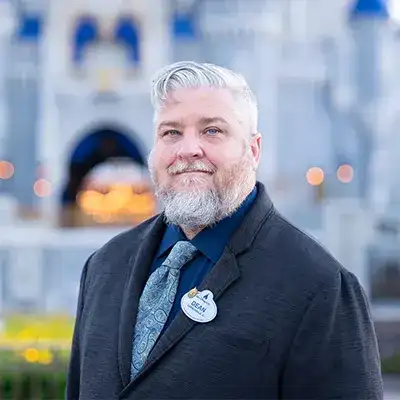 A Disney Cast Member standing with Cinderella Castle in the distance