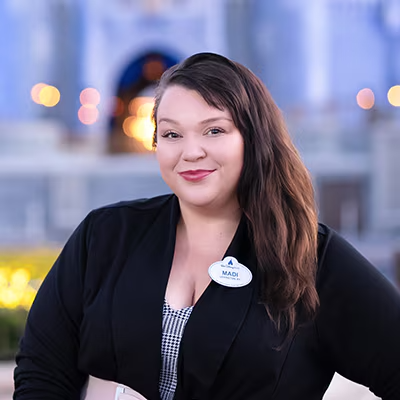 A Disney Cast Member standing with Cinderella Castle in the distance