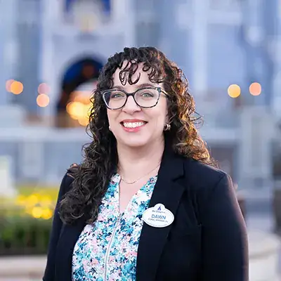 A Disney Cast Member standing with Cinderella Castle in the distance