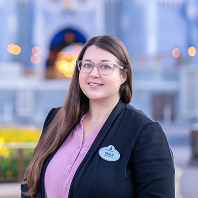 A Disney Cast Member standing with Cinderella Castle in the distance