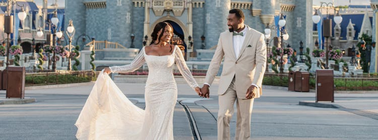 A vow renewal couple walking hand in hand near Cinderella Castle at Magic Kingdom park