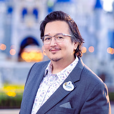 A Disney Cast Member standing with Cinderella Castle in the distance