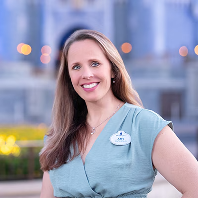 A Disney Cast Member standing with Cinderella Castle in the distance