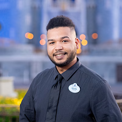 A Disney Cast Member standing with Cinderella Castle in the distance