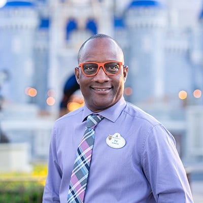 A Disney Cast Member standing with Cinderella Castle in the distance