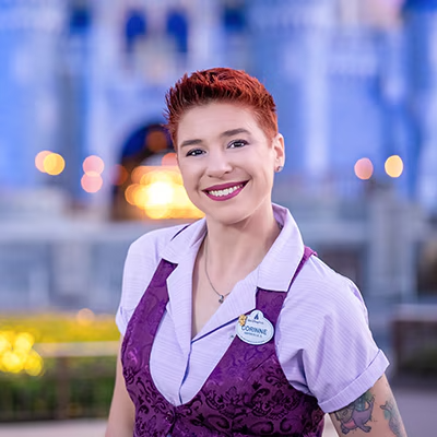 A Disney Cast Member standing with Cinderella Castle in the distance