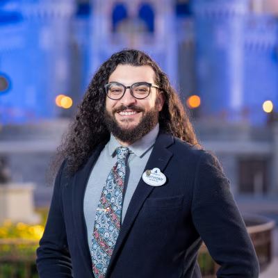 A Disney Cast Member standing with Cinderella Castle in the distance
