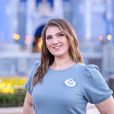 A Disney Cast Member standing with Cinderella Castle in the distance