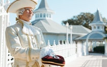 A footman holding a glass slipper on a velvet pillow