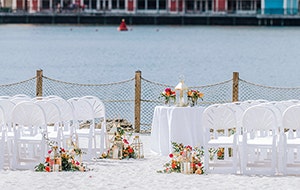 A round table on a beach facing a body of water and Disney’s BoardWalk