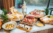 A buffet of charcuterie boards including hummus, cheeses, grapes, dried fruit, crackers, bread and edible flowers