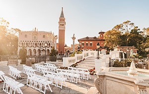 Chairs set up at a wedding venue near a fountain, bridge and tower at Italy Isola in Epcot