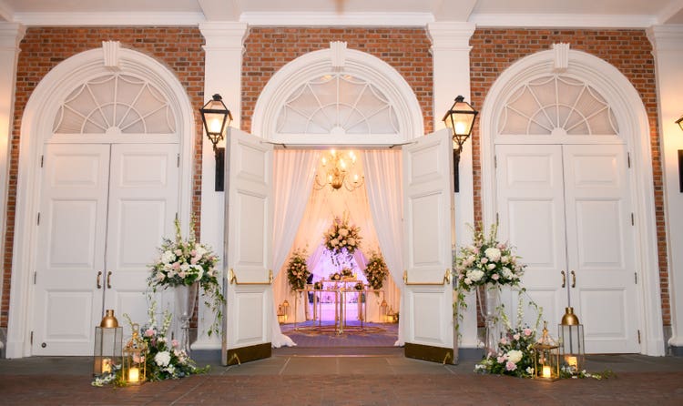 The entrance to The American Adventure framed with flowers and lanterns around the front doors