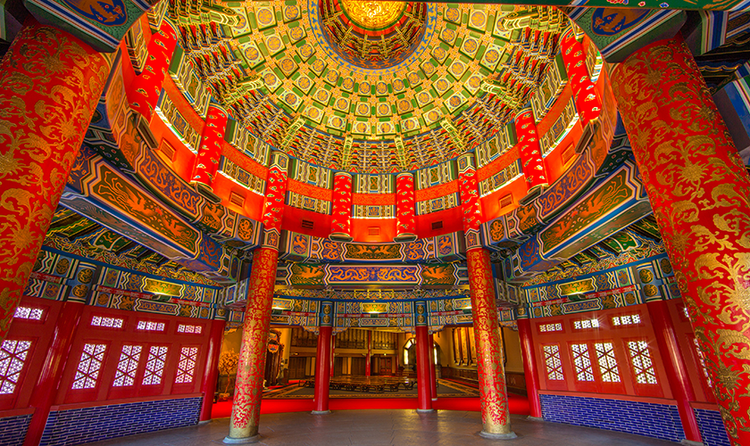 A large, unfurnished room with traditional Chinese design patterns on the walls, pillars and ceilings