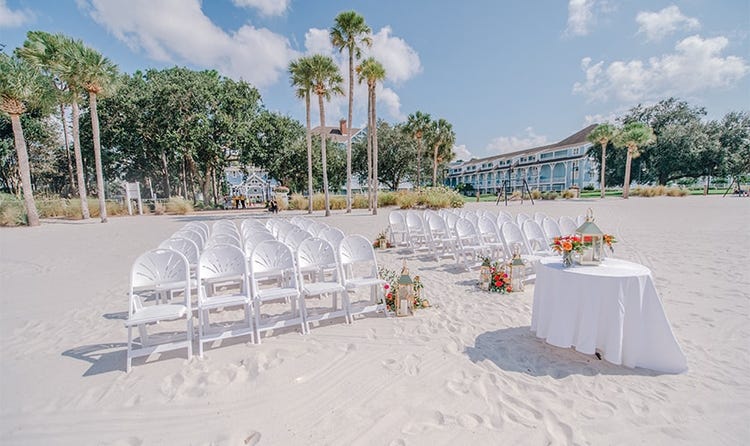 A round table holding a lantern on a beach with several rows of chairs