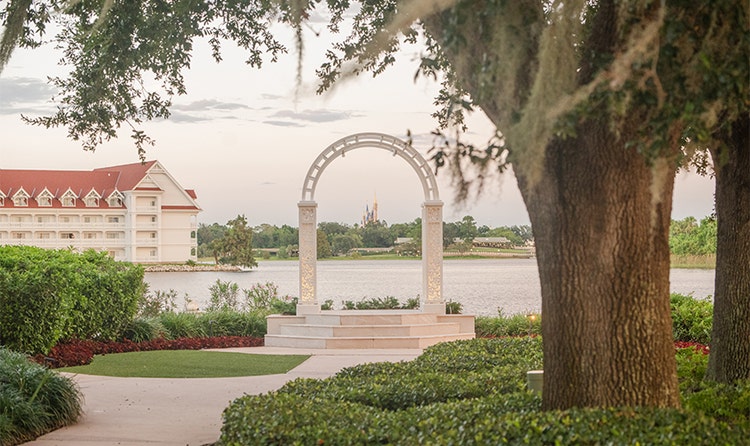 Cinderella Castle is visible through the arch of an outdoor altar at Disney’s Wedding Pavilion