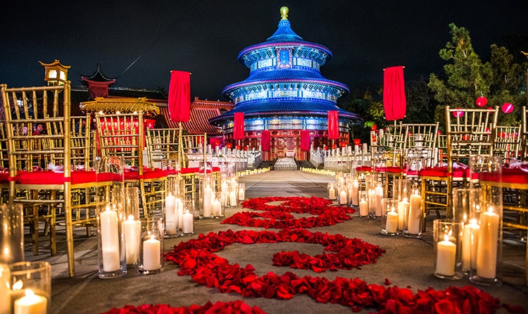Chairs with clusters of lit candles along an aisle of swirled rose petals at the China Pavilion
