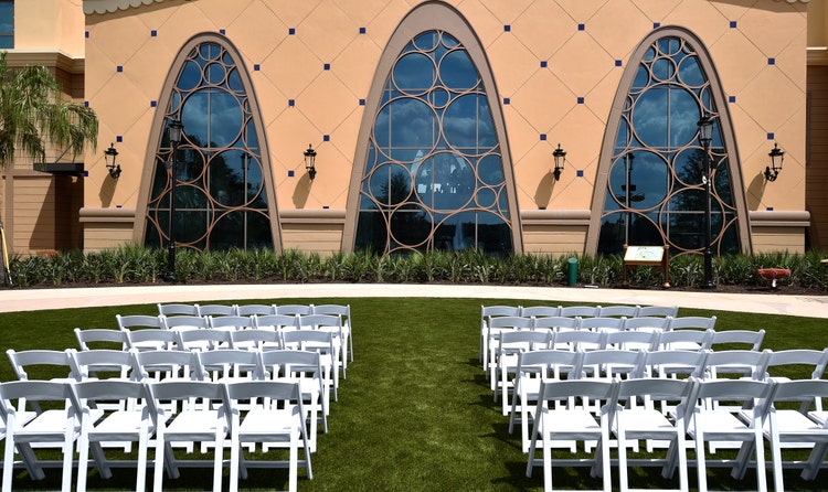 An aisle flanked by two sets of chairs ends in front of a large building