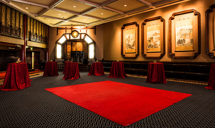 Several cocktail tables in a room with Chinese inspired artwork on the walls