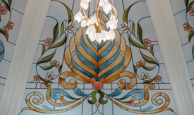 A floral chandelier hanging in front of a stained glass window