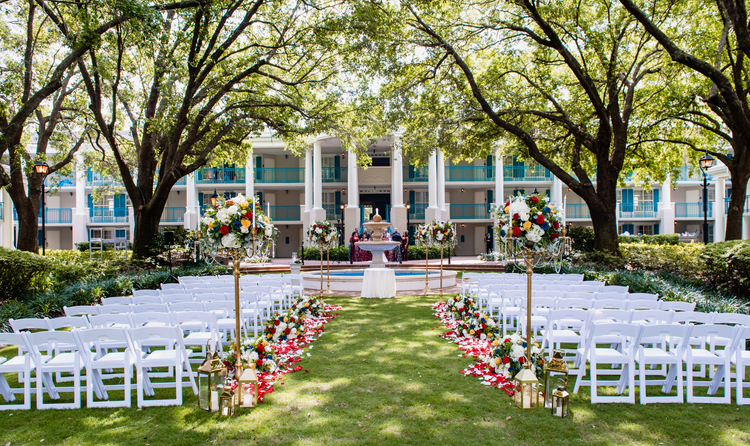 Rows of chairs line an aisle leading to a circular archway in front of Oak Manor at Disney’s Port Orleans Riverside