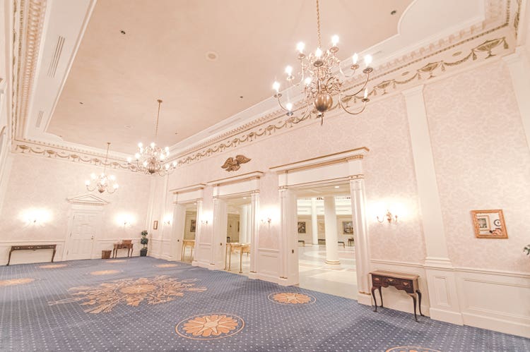 A carpeted room leading to doors connecting to the rotunda at The American Adventure in EPCOT