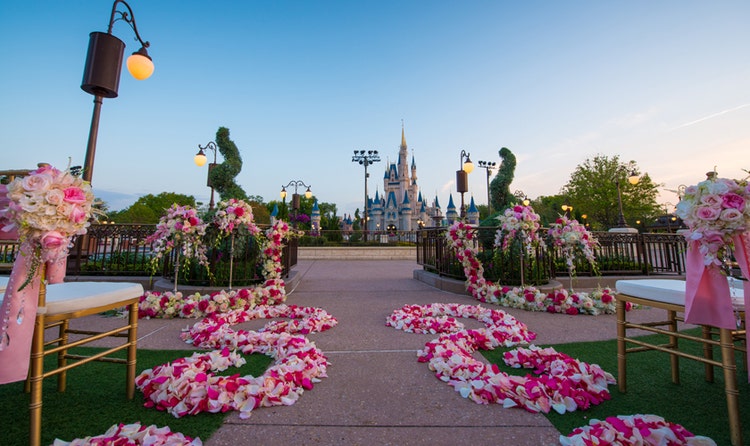 Cinderella's Castle stands in the background of an outdoor wedding venue set with chairs and floral arrangements